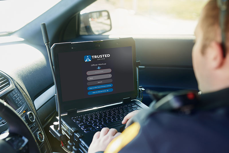 Police officer with laptop inside cruiser looking at TrustedDriver app
